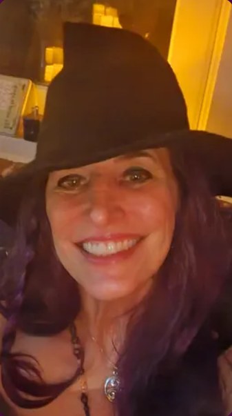 Patty Moloney Figliola, smiling, in a dark wide-brimmed hat