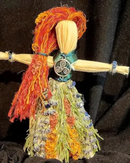 Doll of the goddess Brigid: red-orange hair and a skirt of lavender and marigold