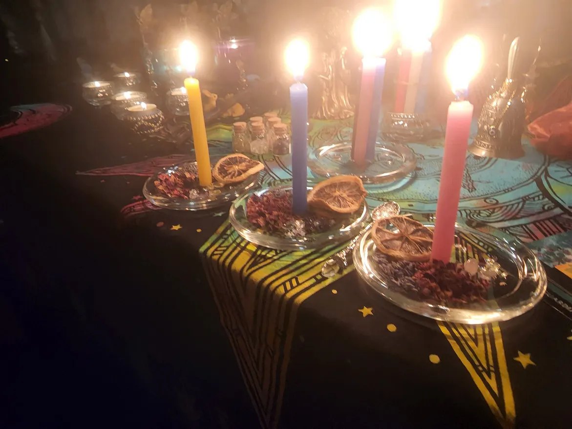 A Sabbat altar with lit candles, dried citrus, herbs and crystals