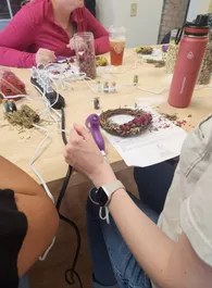 A guest using a glue gun on a floral wreath