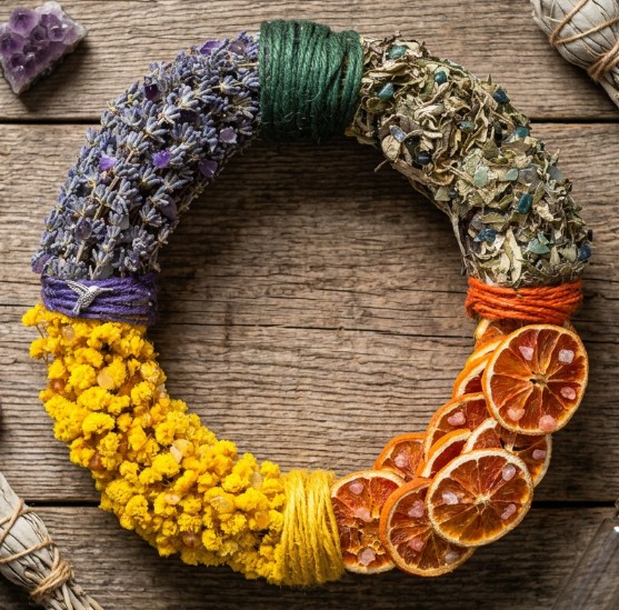 Midsummer wreath in bands of purple lavender, bright yellow yarrow and dark forest greens with dried orange slices