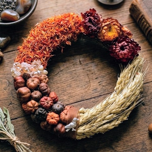 Mabon wreath of safflower, strawflowers, small pods and wheat with a raven charm